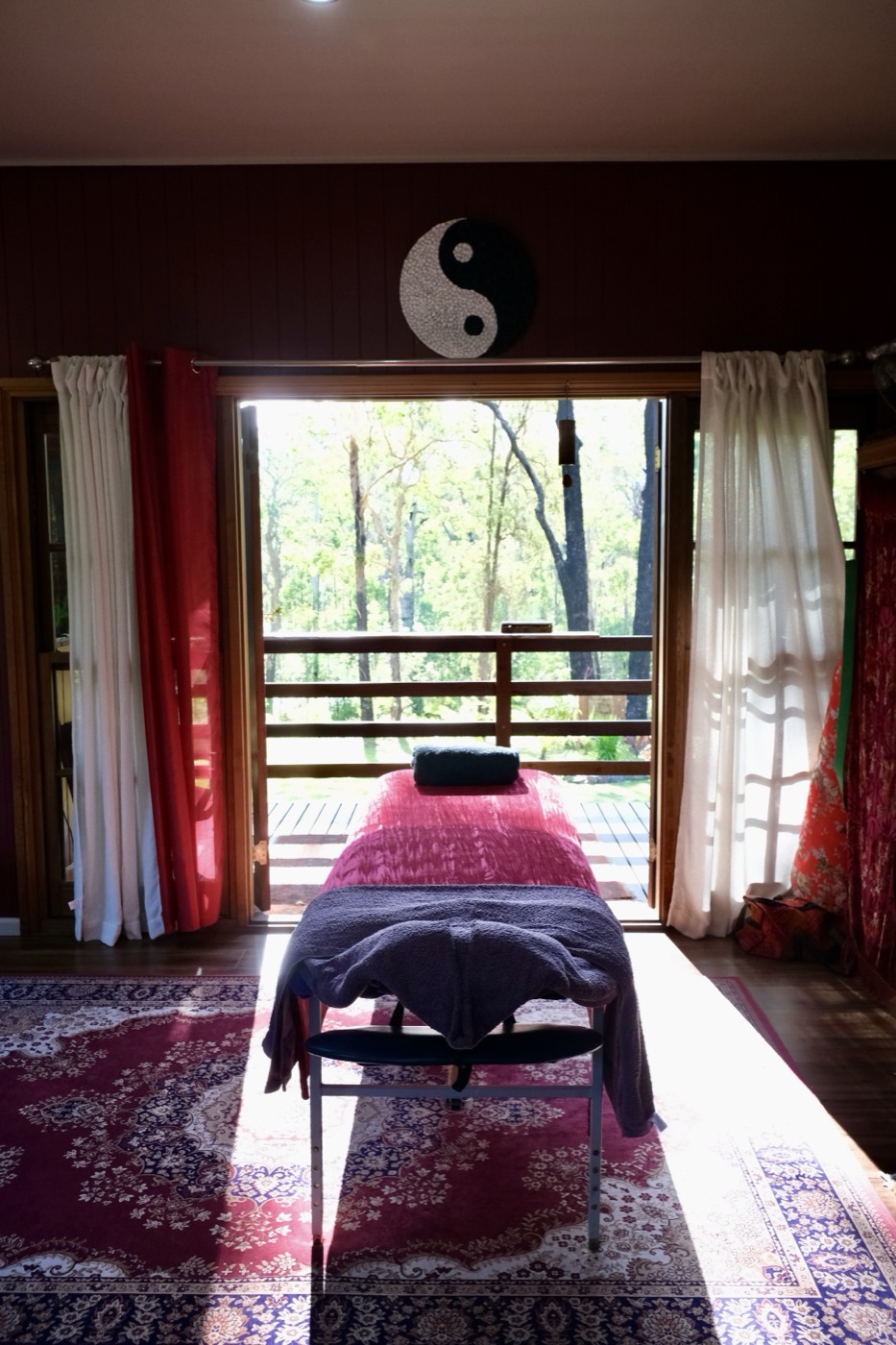 The treatment room at Shalom, with a massage table and doors open to the trees